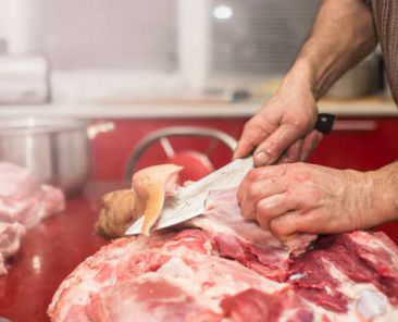 Man slicing pork meat on a table, close-up, conceptual idea
