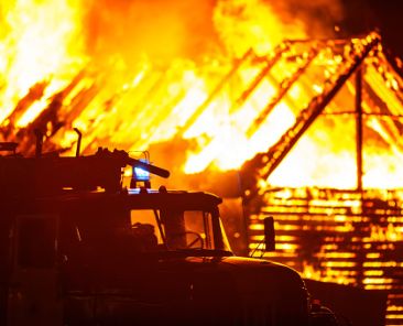 Arson or nature disaster - burning fire flame on wooden house rooft